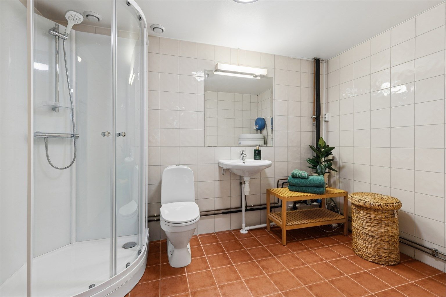 Delikat og funksjonelt bad med dusjkabinett, gulvvarme og tilrettelagt plass for vaskemaskin og tørketrommel.