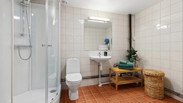 Delikat og funksjonelt bad med dusjkabinett, gulvvarme og tilrettelagt plass for vaskemaskin og tørketrommel.