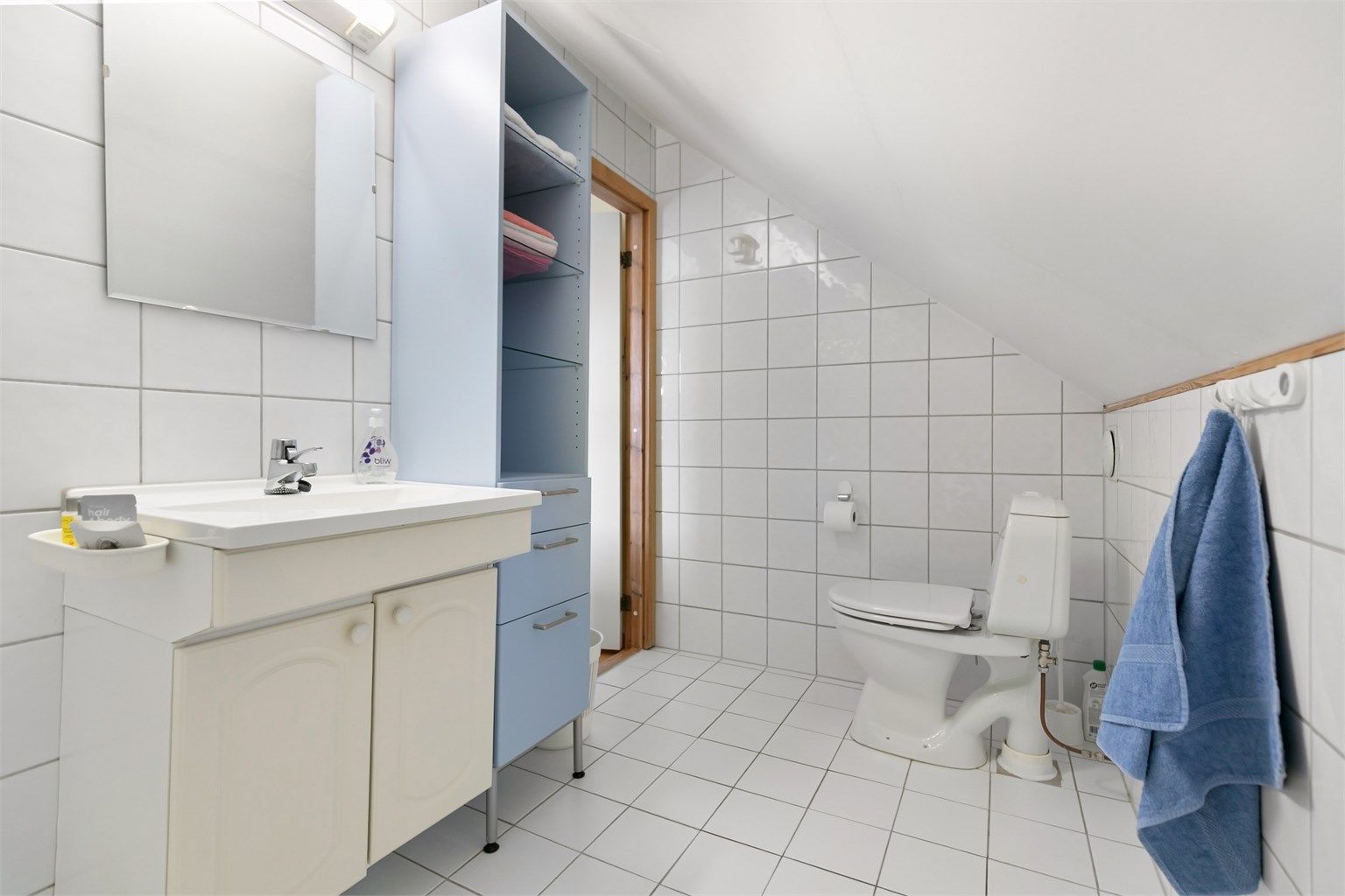 Flislagt bad med plass til ekstra oppbevaringsmøbler.