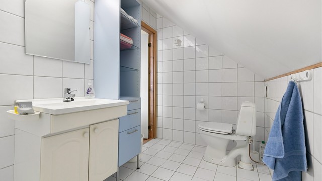 Flislagt bad med plass til ekstra oppbevaringsmøbler.