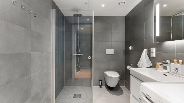 Badet holder en gjennomført standard med flislagt gulv med gulvvarme. flislagte vegger og nedsenket himling med downlights