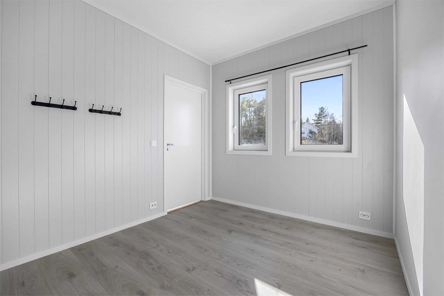 Soverommet har malte plater på veggene og laminatgulv, en gjennomgående standard i boligen.
