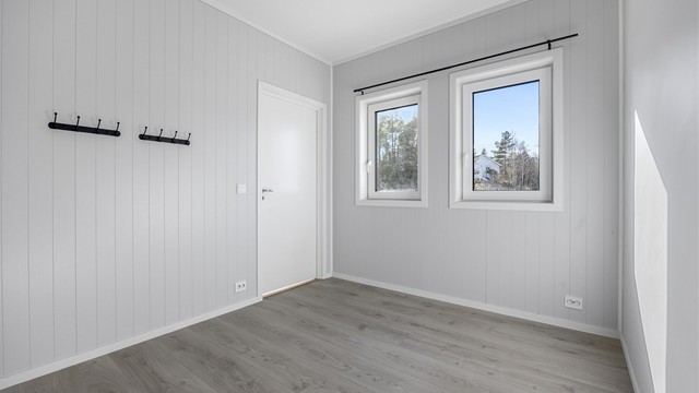 Soverommet har malte plater på veggene og laminatgulv, en gjennomgående standard i boligen.