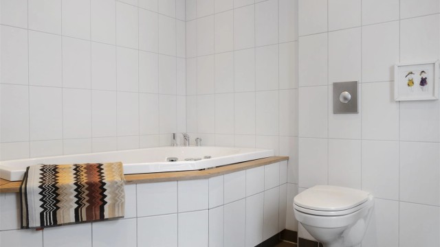 Badet er utstyrt med innbygget badekar og veggmontert toalett.