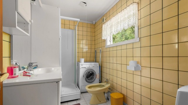 Badet er innredet med servant, toalett, dusj og opplegg for vaskemaskin.