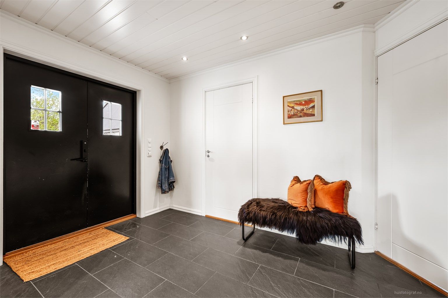 Entré med flislagt gulv, gulvvarme og innfelte downlights i himlingen. Herfra er det utgang til en platting ved inngangspartiet.