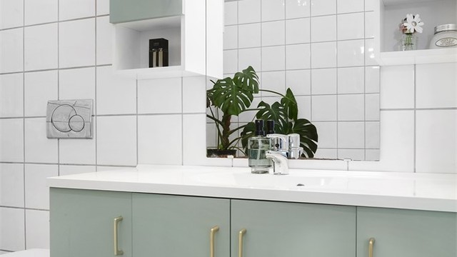 Servantinnredning med god oppbevaringsplass, vegghengt toalett og speil med overlys.