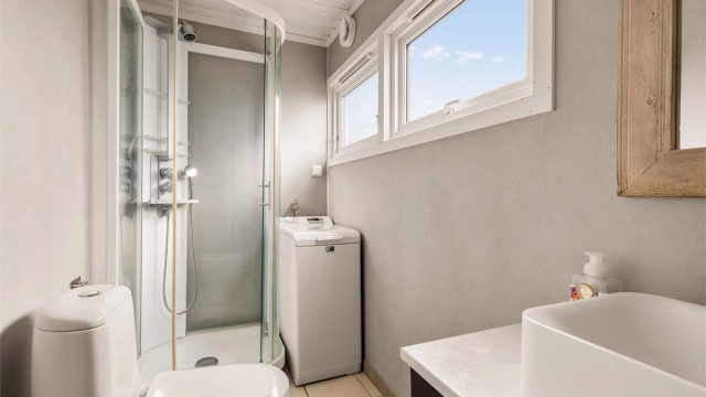 Pent bad med flislagt gulv og varmekabler. Vegger med våtromsplater og tak med malt trepanel. Badet ble modernisert og oppgradert med nye våtromsplater i 2024.