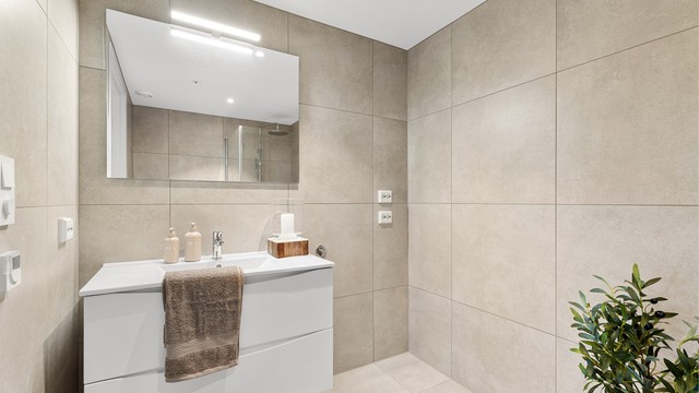 Badet har 60x60 fliser på gulv og vegger, opplegg til vaskemaskin og tørketrommel samt en større servant med oppbevaring.