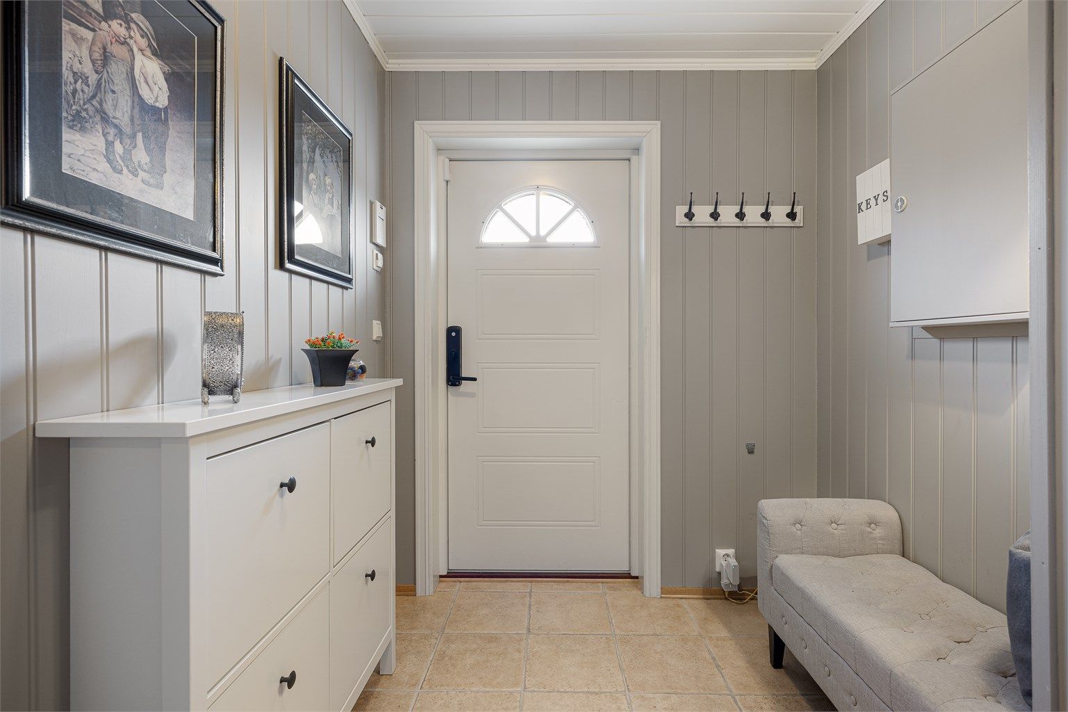 Inngangspartiet er innbydende med flislagt gulv og varmekabler. Ytterdøren er utstyrt med kodelås for enkel adkomst.