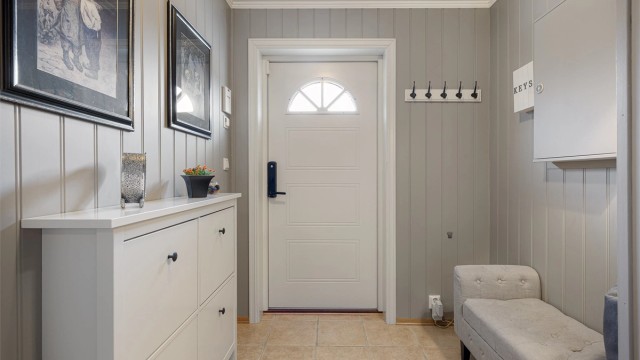 Inngangspartiet er innbydende med flislagt gulv og varmekabler. Ytterdøren er utstyrt med kodelås for enkel adkomst.