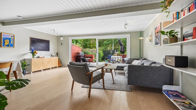Store skyvedører med vindusflater gir lett adgang til uteområdet og tilfører stuen naturlig lys og velvære.