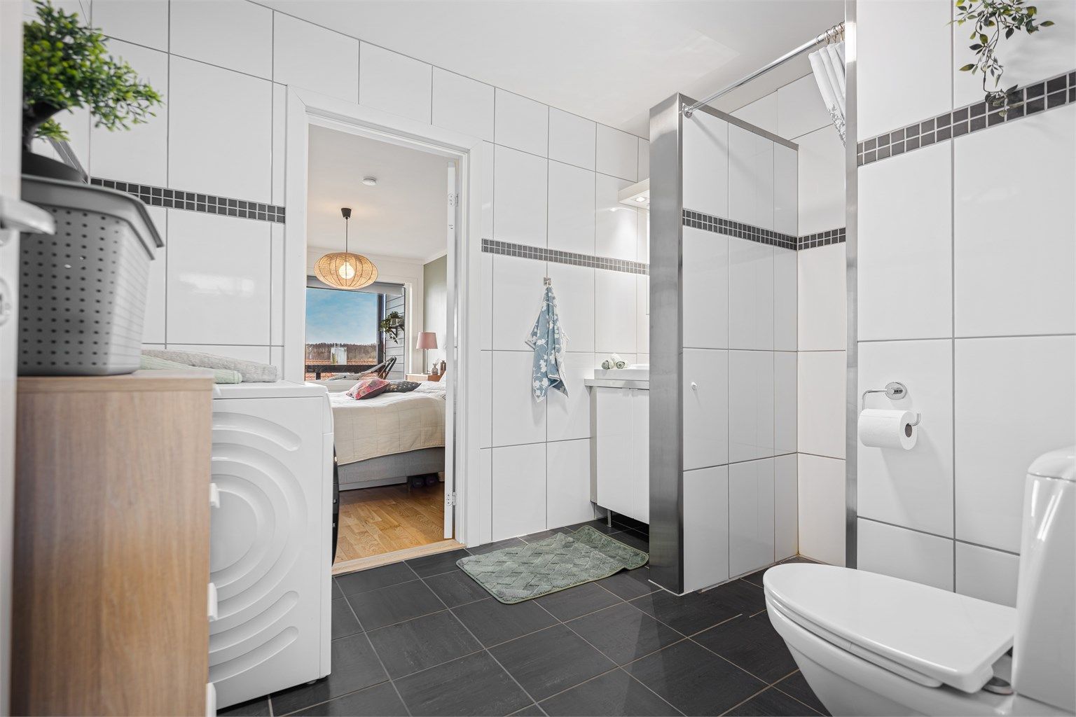 Helfliset bad av god størrelse og direkte tilgang til soverom. Det er varmekabler i gulv, servant og speilskap på vegg. Toalett, dusjnisje og opplegg for vaskemaskin. 