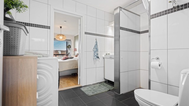 Helfliset bad av god størrelse og direkte tilgang til soverom. Det er varmekabler i gulv, servant og speilskap på vegg. Toalett, dusjnisje og opplegg for vaskemaskin.