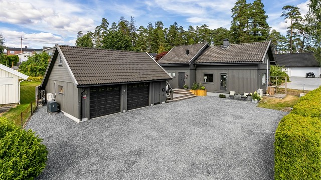 Lader til EL-bil er montert på garasjens yttervegg, mot gårdsplassen.