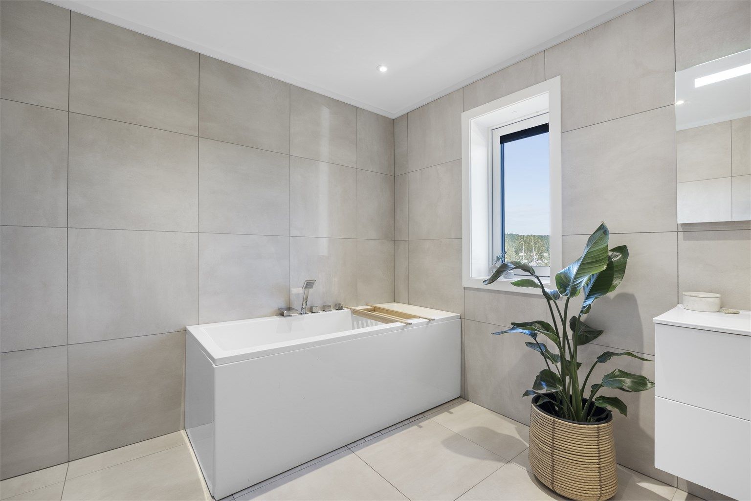 Badet i første etasje er fra byggeår, med flislagte overflater, vannbåren gulvvarme og badekar.