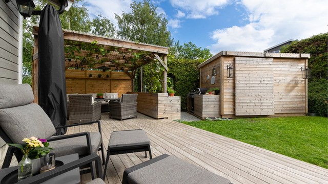 Et velholdt enderekkehus med en stor, usjenert hage som inkluderer pergola og et praktisk utekjøkken.
