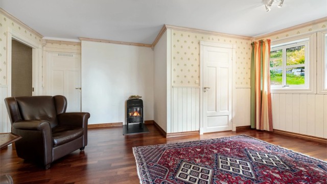 Kjellerstue med vedovn og parkett på gulvet.