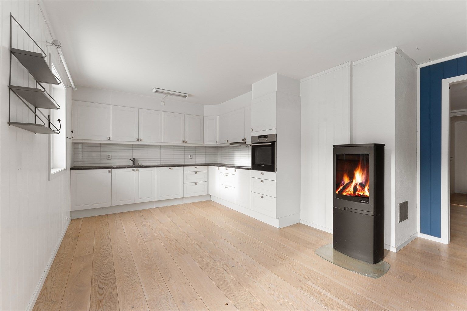 Kjøkkenet er plassert i åpen løsning mot stuen, med peisovnen som et sentralt element.