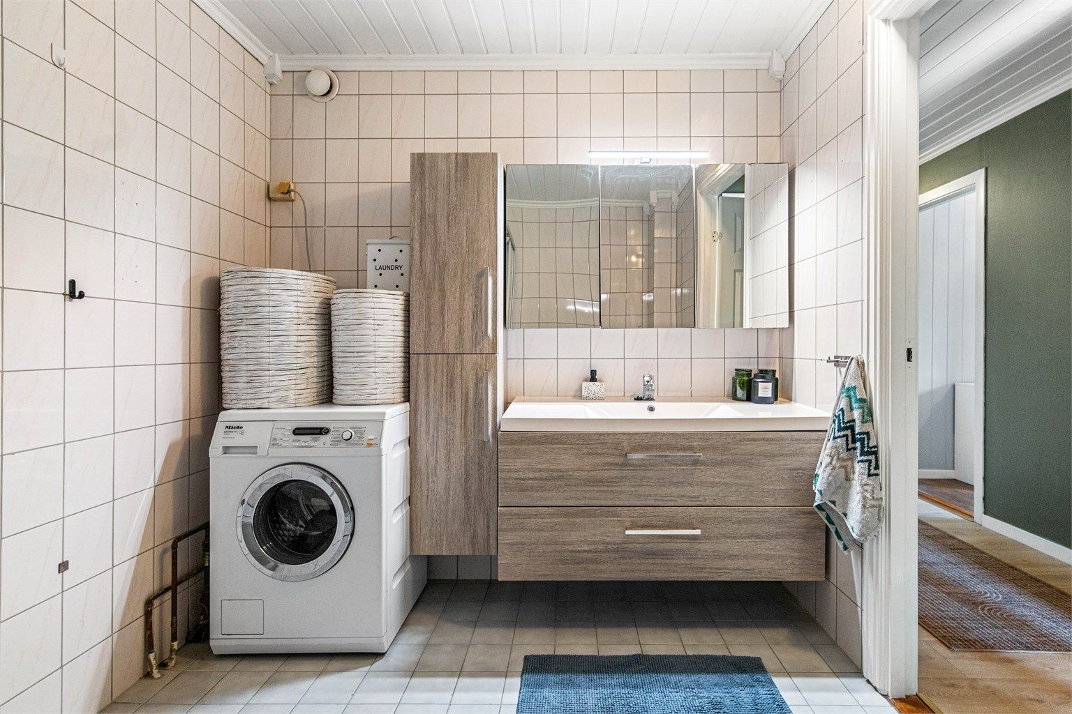 Badet er romslig, med fliser på gulv og vegger. Det er varmekabler i gulvet.