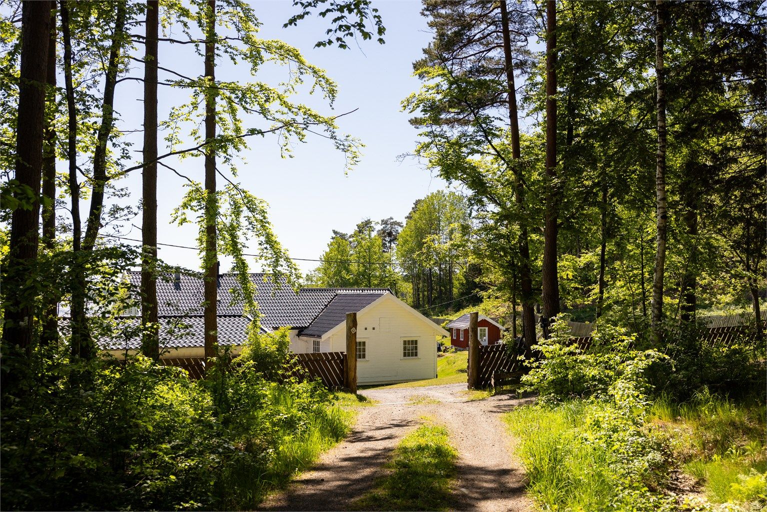 Bak et hyggelig gjerde, gjennom en port, ligger Fuglevik