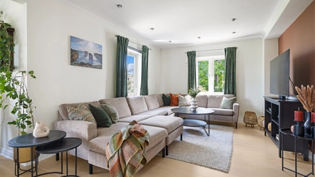 Den hyggelige sofakroken danner et naturlig samlingspunkt i stuen, med TV-sone og behagelig belysning fra downlights.