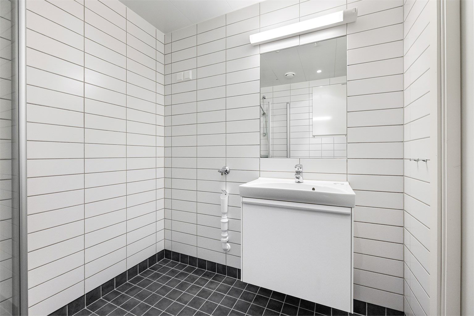 Praktisk dusjhjørne med innfellbare glassdører og opplegg for vaskemaskin.