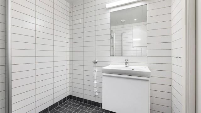 Praktisk dusjhjørne med innfellbare glassdører og opplegg for vaskemaskin.