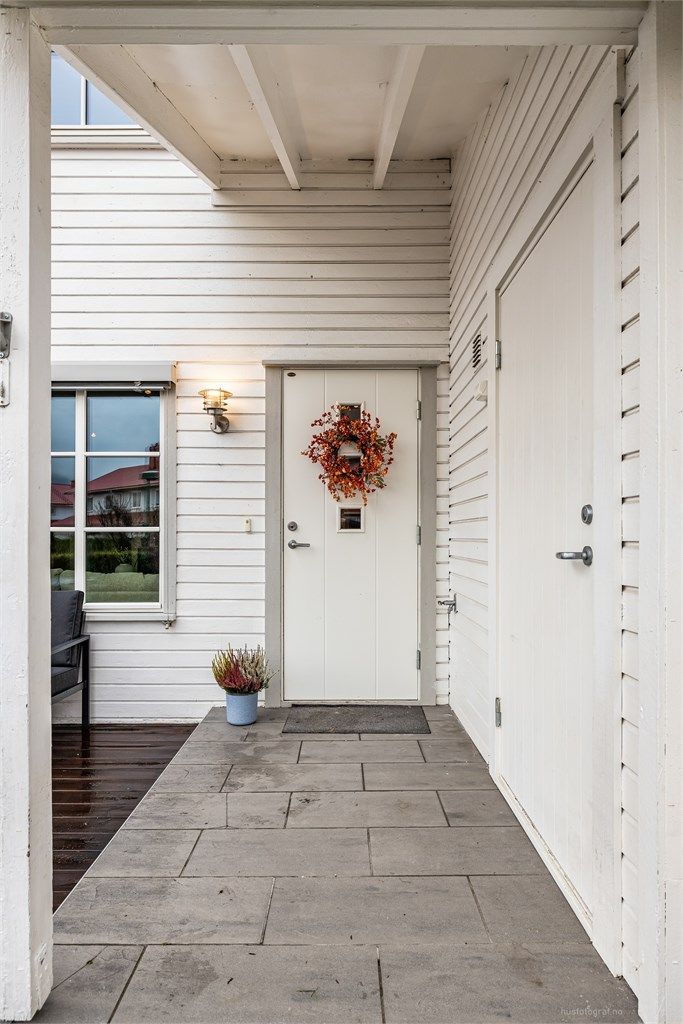 Adkomstvei belagt med belegningsstein til boligens flislagte og overbygde inngangsparti i 1. etasje.