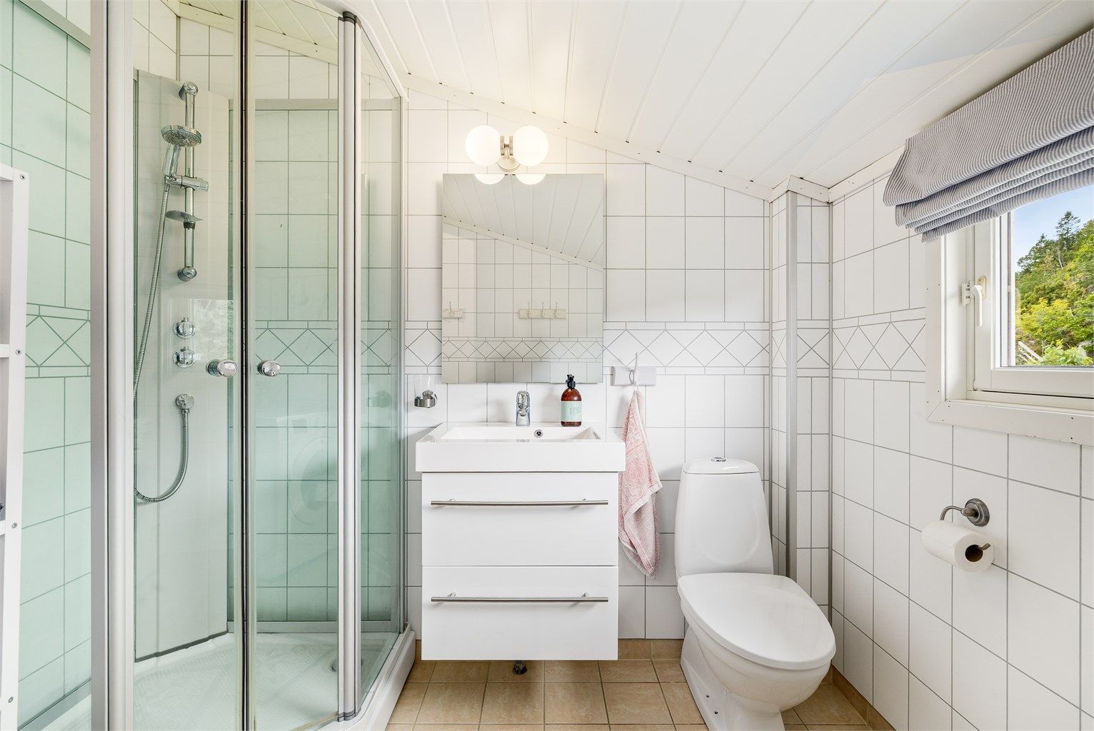 Badet har servant med skuffeseksjon under, wc, dusjkabinett og opplegg til vaskemaskin.