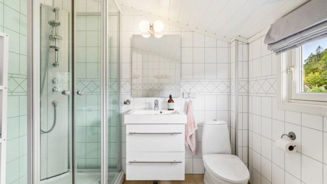 Badet har servant med skuffeseksjon under, wc, dusjkabinett og opplegg til vaskemaskin.
