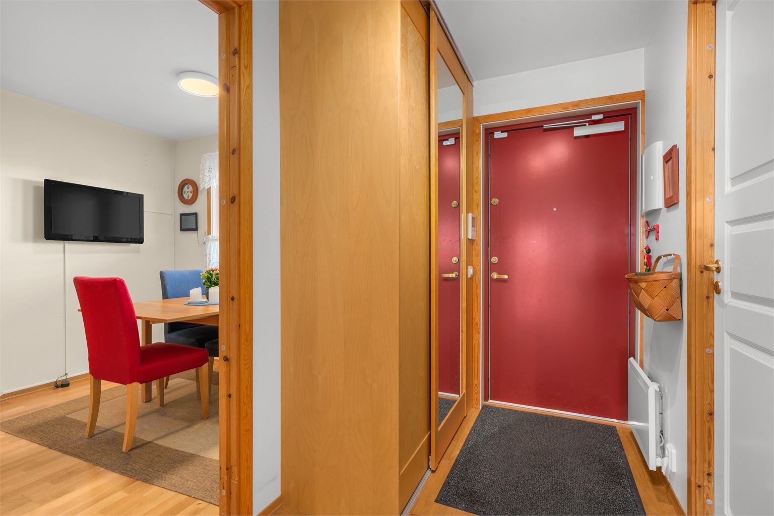 Entréen har tre-stavs parkett på gulvet og en praktisk skyvedørsgarderobe med speilfronter.