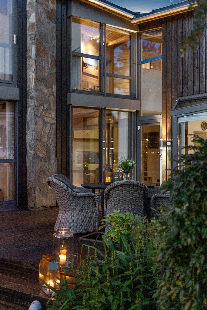 Arkitektonisk fasade med naturstein og store vinduspartier sett fra terrassen.