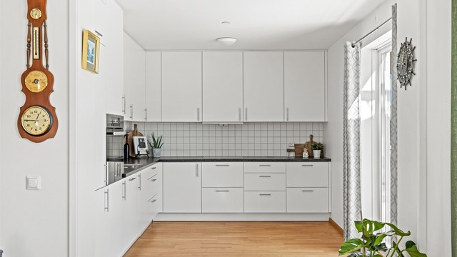 Kjøkkeninnredning fra byggeåret med glatte fronter og laminert benkeplate. Det er godt med skap- og benkeplass.