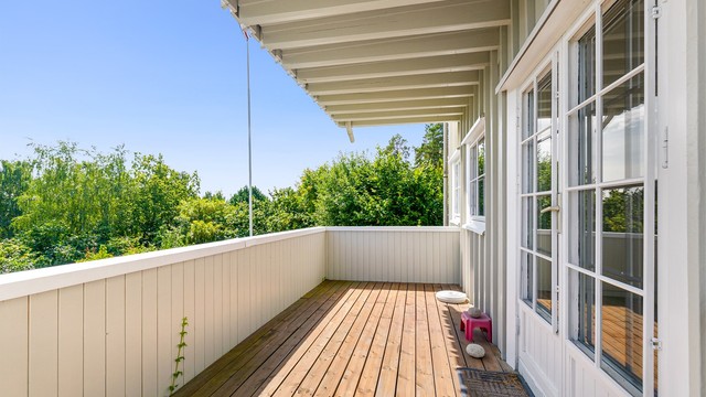 Sydøstvendt balkong på 11 m² med terrassebord og rekkverk i tre.