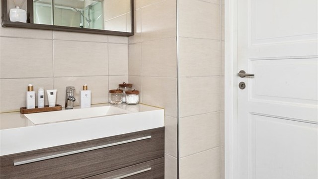 Badet i loftsetasjen ble oppgradert i 2010 og fremstår som delikat med beige veggfliser, brune gulvfliser, gulvvarme og hvitmalt himling med downlights.