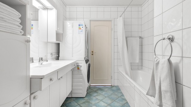 Badet er innredet med vegghengt servantinnredning med ovenpåliggende servant og armatur, samt speil, belysning med stikkontakt og skap på vegg over servant. Det er opplegg for vaskemaskin, gulvstående toalett og innebygd badekar med dusjforheng.