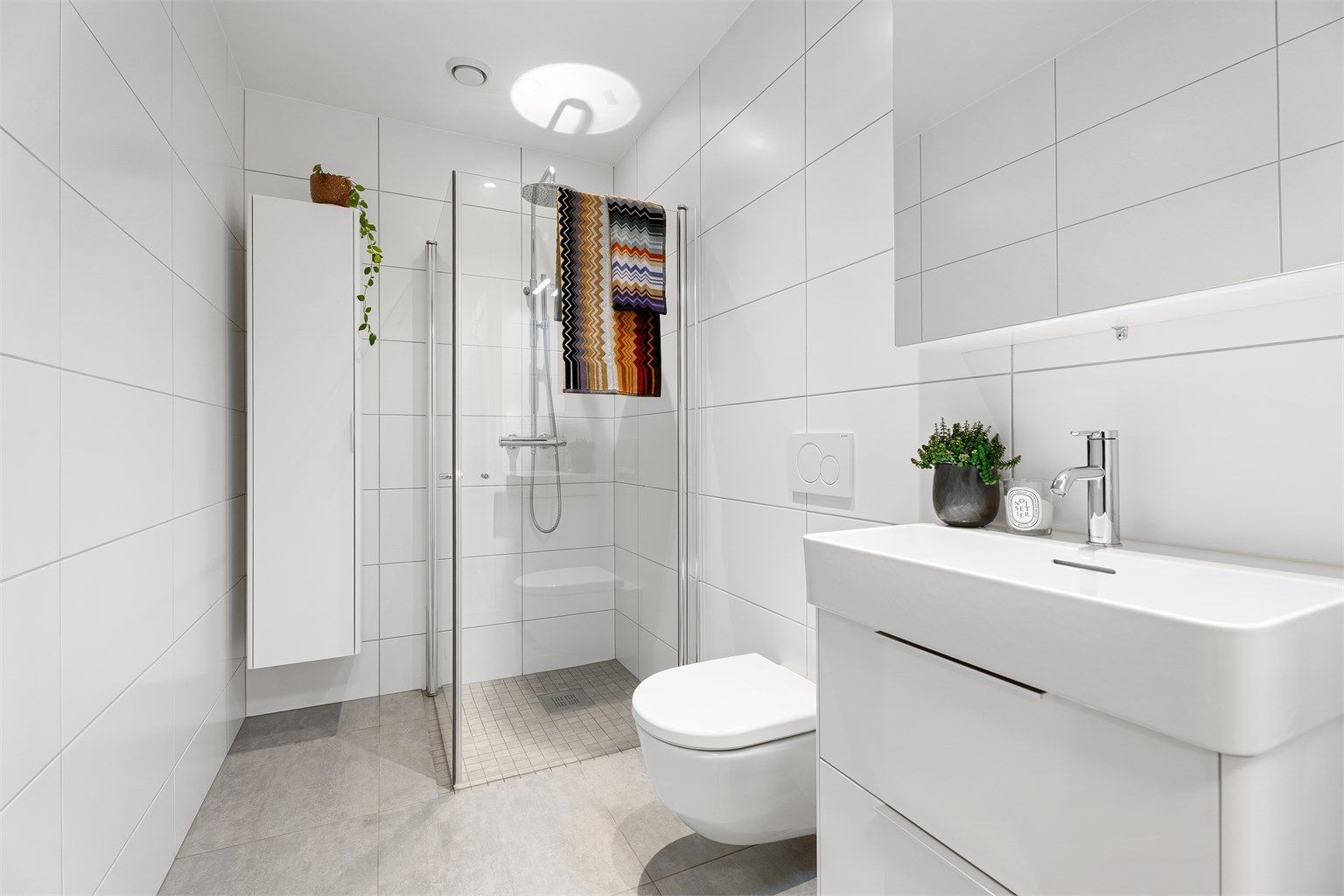 Badet har en tidløs og moderne stil og byr på blant annet dusjnisje med innfellbare dører og regndusj. Det er også baderomsinnredning med plass til ekstra oppbevaring. 