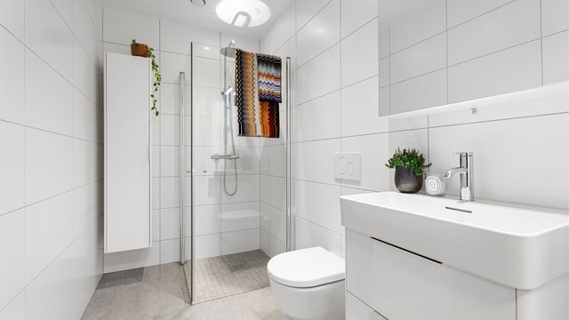 Badet har en tidløs og moderne stil og byr på blant annet dusjnisje med innfellbare dører og regndusj. Det er også baderomsinnredning med plass til ekstra oppbevaring.
