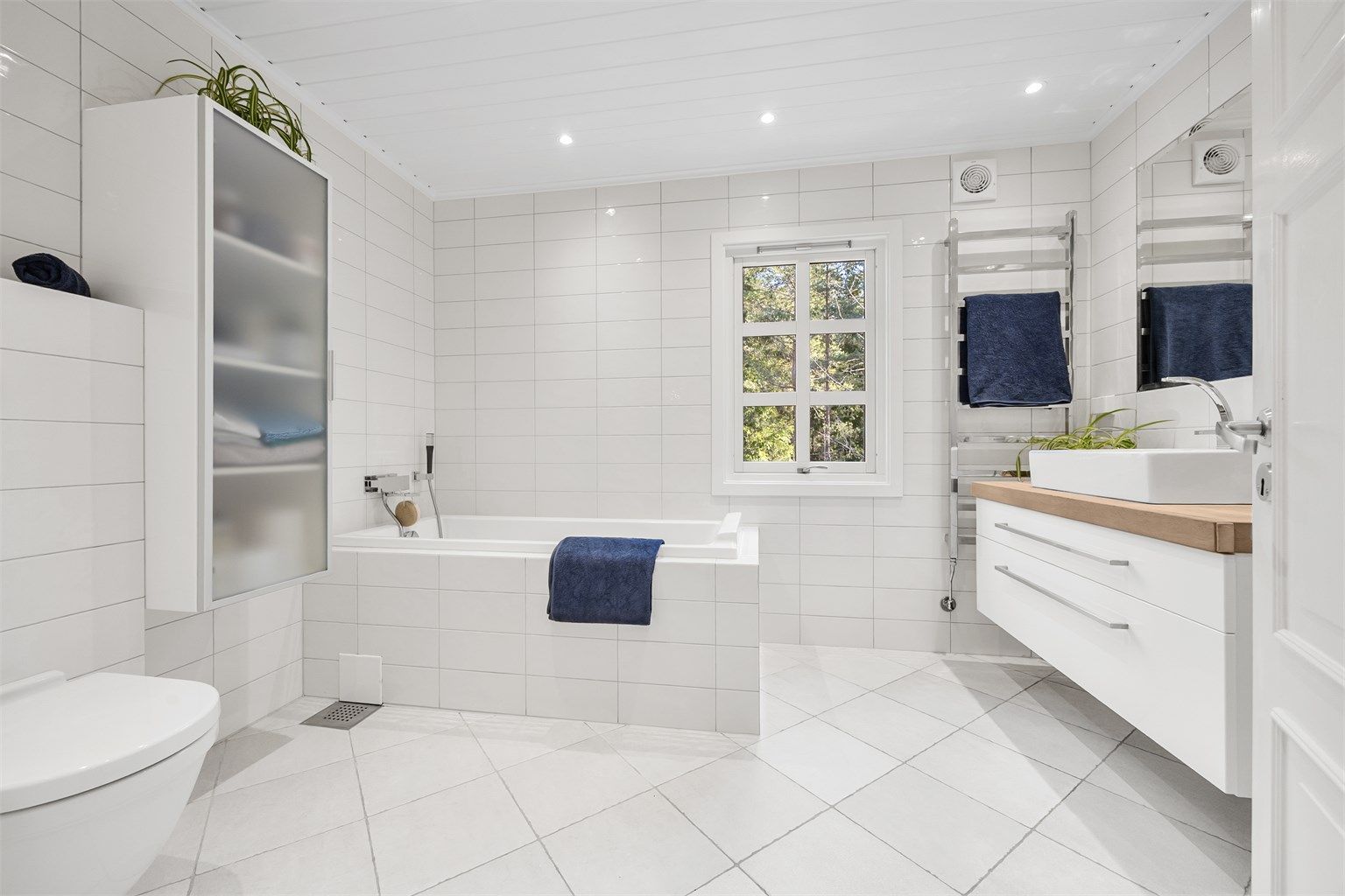 Lekkert flislagt bad med badekar og dusjhjørne. 