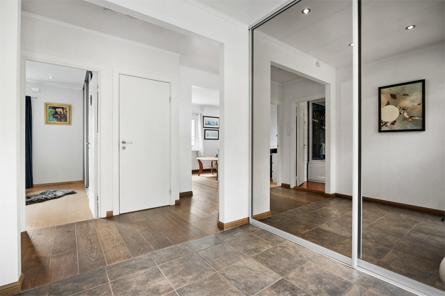 Entré med flislagt gulv, vannbåren gulvvarme og romslig skyvedørsgarderobe.