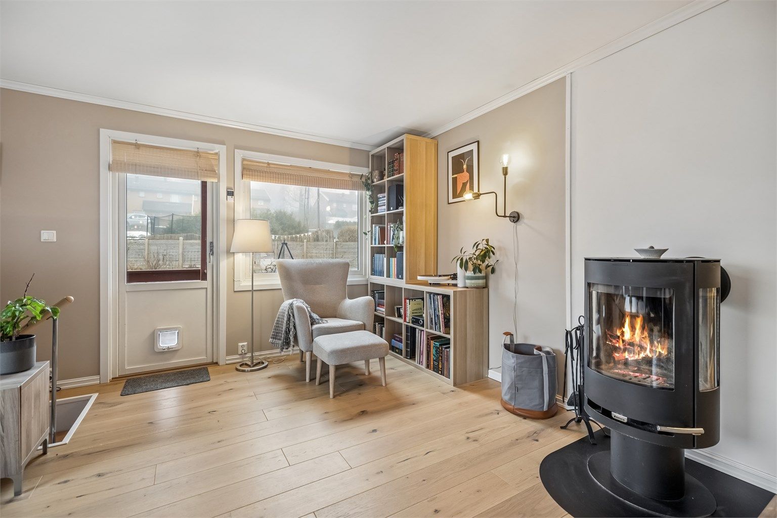 Stuen får godt med naturlig lys fra store vinduer. Det er hyggelig å sitte i godstolen å høre på musikk eller lese en bok samtidig som man kan se på flammene fra peisen.