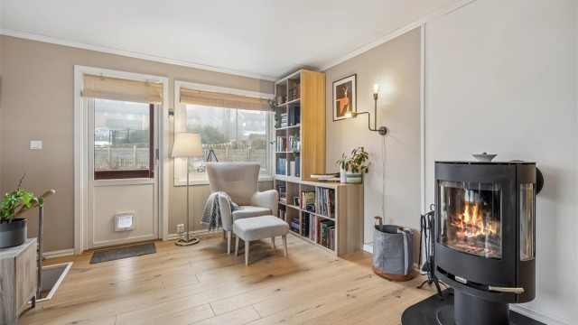 Stuen får godt med naturlig lys fra store vinduer. Det er hyggelig å sitte i godstolen å høre på musikk eller lese en bok samtidig som man kan se på flammene fra peisen.