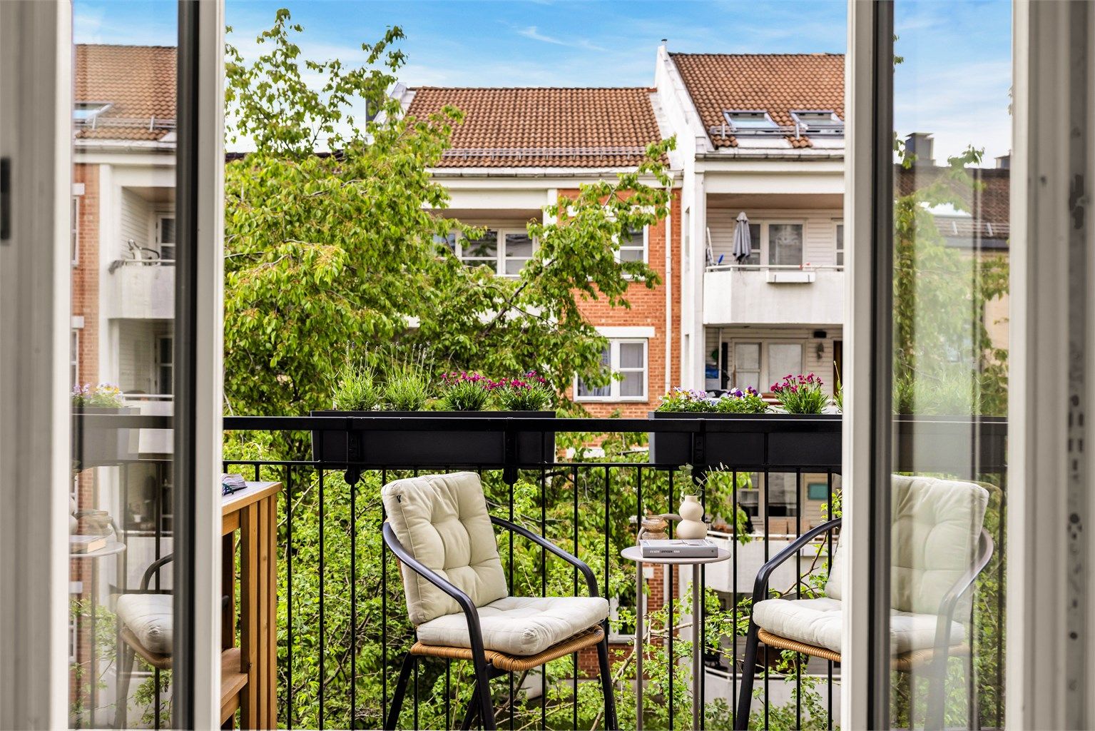 Romslig balkong som vender mot skjermet og frodig bakgård. 