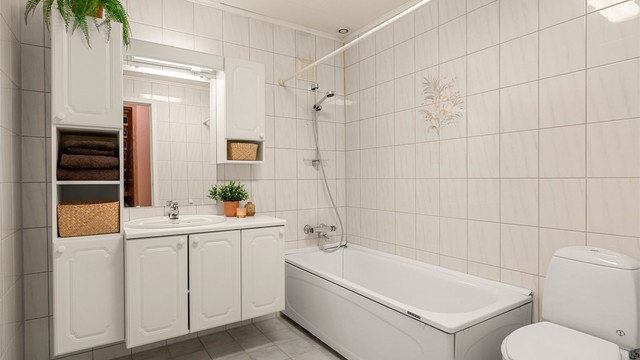Badet i kjelleren har flislagte overflater, gulvvarme, badekar, servantinnredning og toalett.