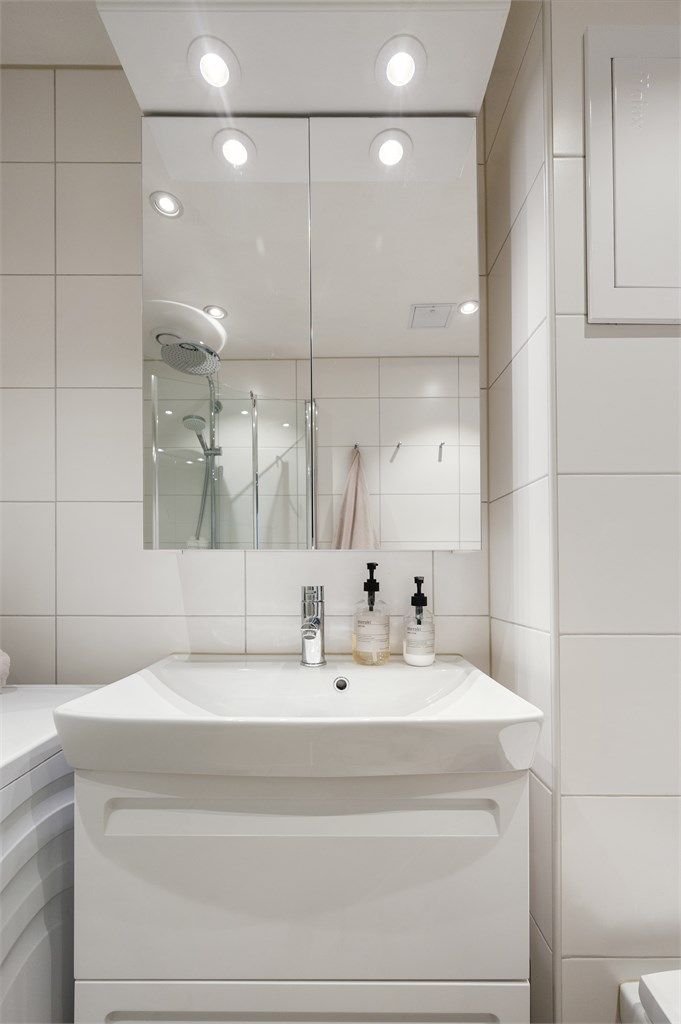 Det er vegghengt toalett, dusjhjørne og servant med skuffer for oppbevaring.