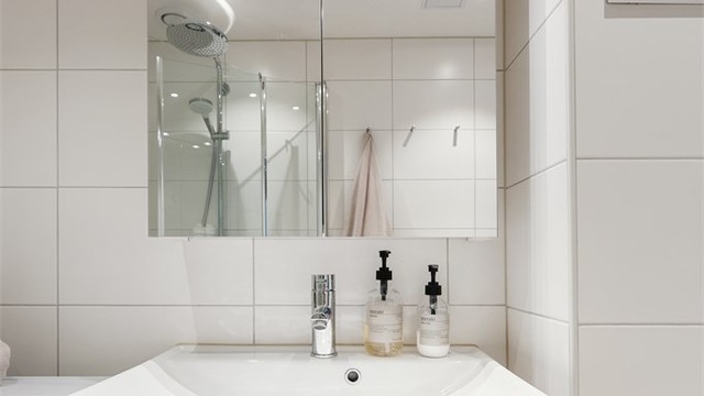 Det er vegghengt toalett, dusjhjørne og servant med skuffer for oppbevaring.