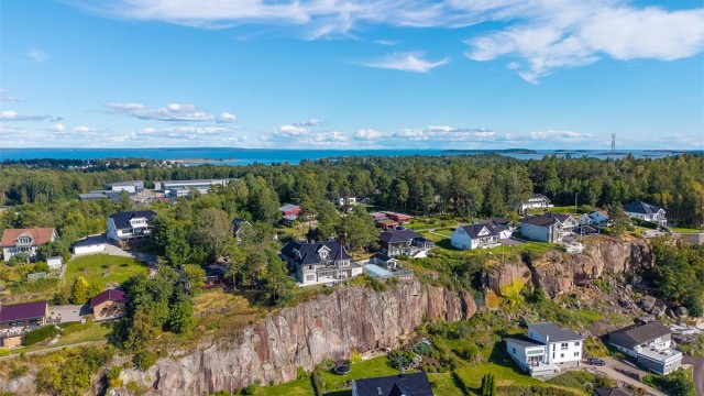 Tomten er omgitt av trær som skaper både skjerming og en naturlig ramme rundt eiendommen.
