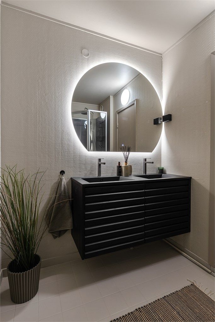 Baderom med flislagt gulv. Tapet på vegger. Malte flater i himling. Dobbel ovenpåliggende servant med armaturer. Speil med sidelys. Dusjkabinett med dusjarmatur.  Mekanisk avtrekk med ventil i vegg. TIlgang fra entré og fra hovedsoverommet.
