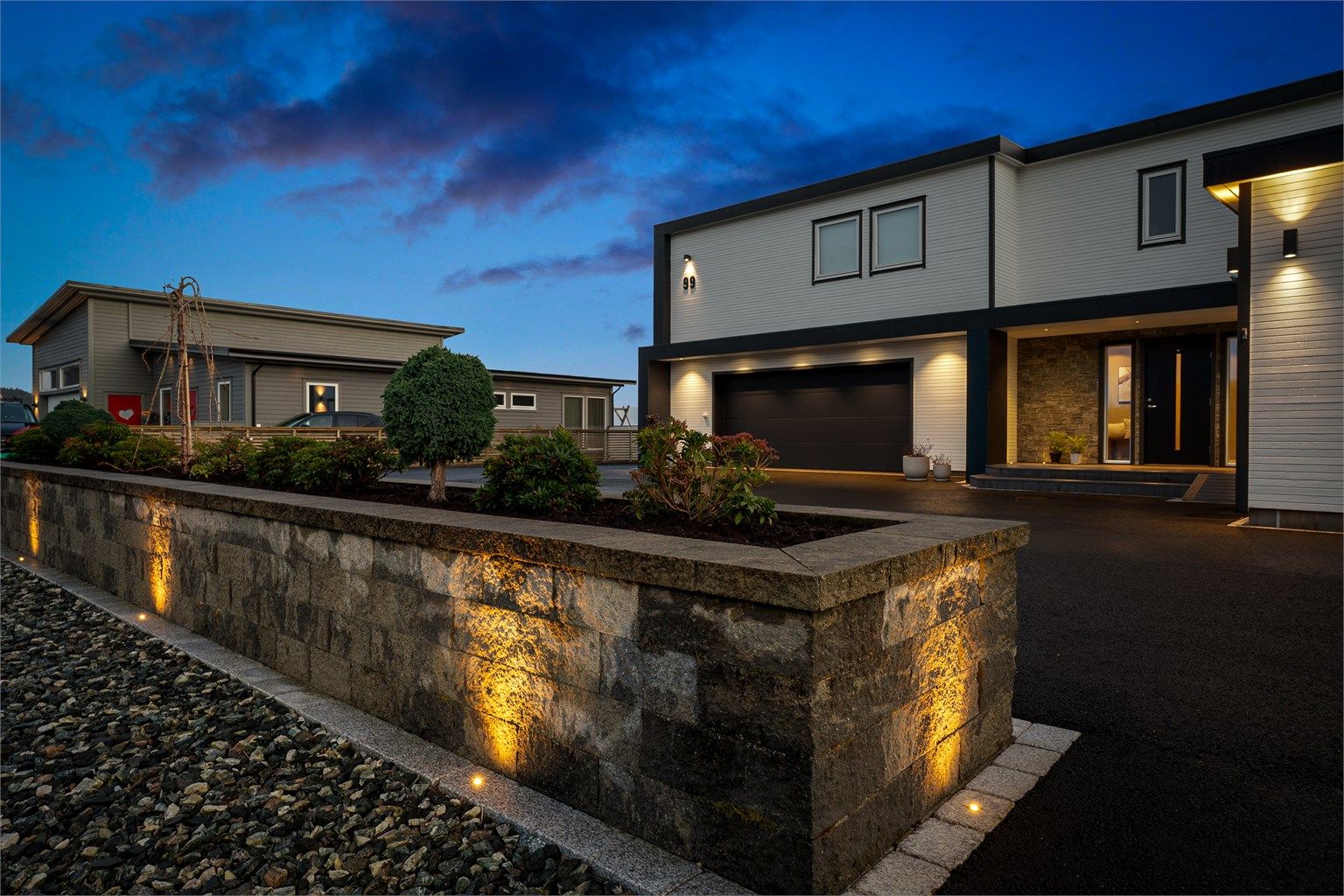 Nydelig mur med integrert bed som deler eiendommen fra tilkomstveien. Nydelig belysning rundt murkanten.